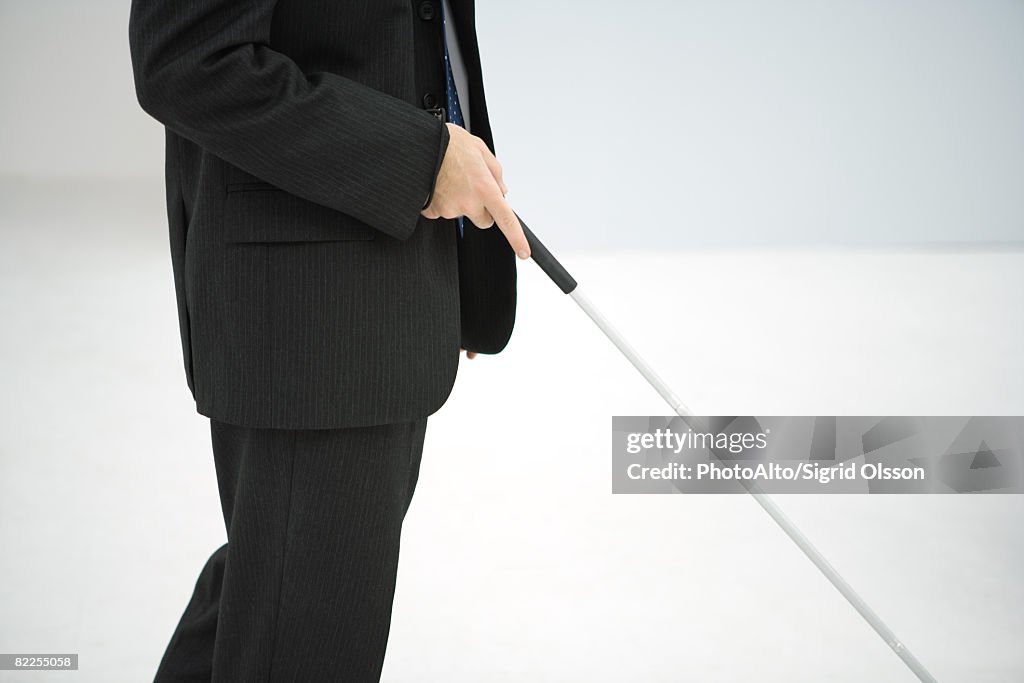Businessman walking with white cane, cropped view