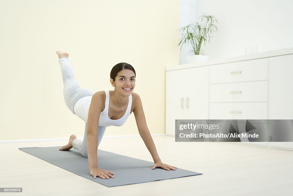 Woman down on all fours, exercising, smiling at camera