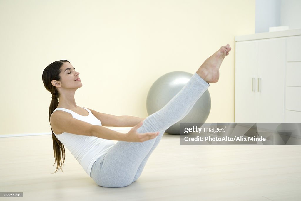 Woman performing boat pose, side view