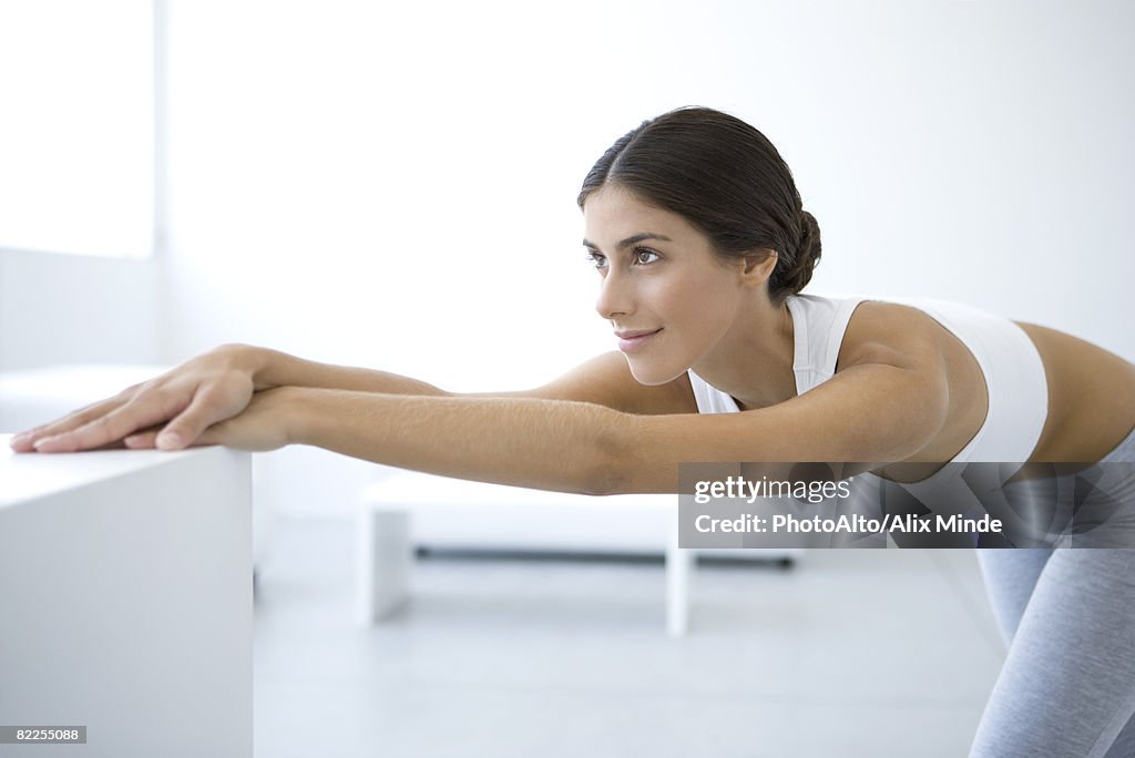 Woman stretching, bending over, arms outstretched