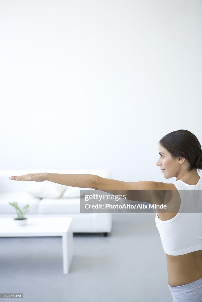 Woman stretching, one arm extended, side view