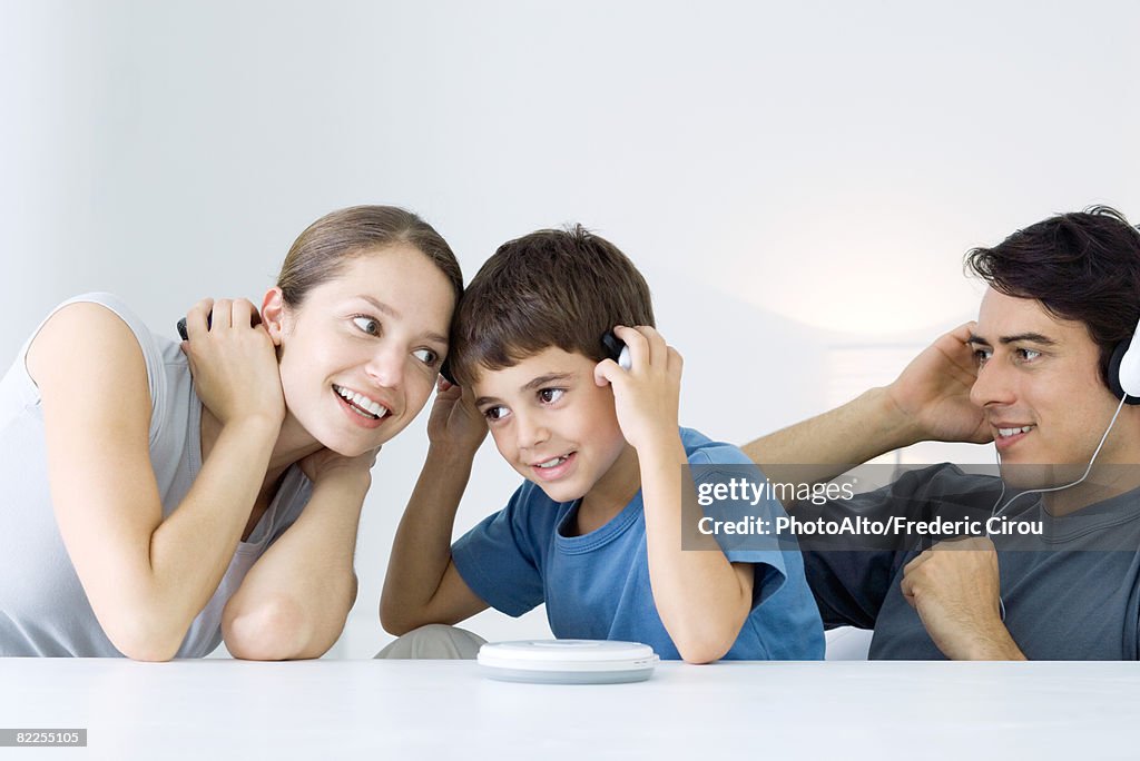 Family listening  to CD player together, mother and son sharing headphones