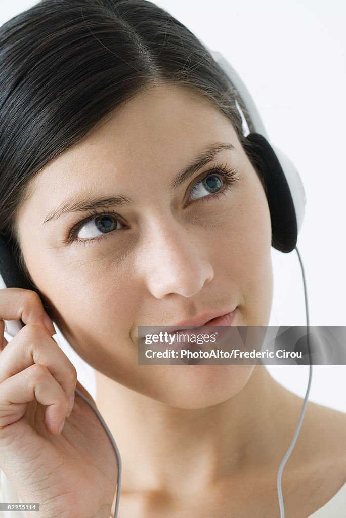 Young woman listening to headphones, smiling, looking away
