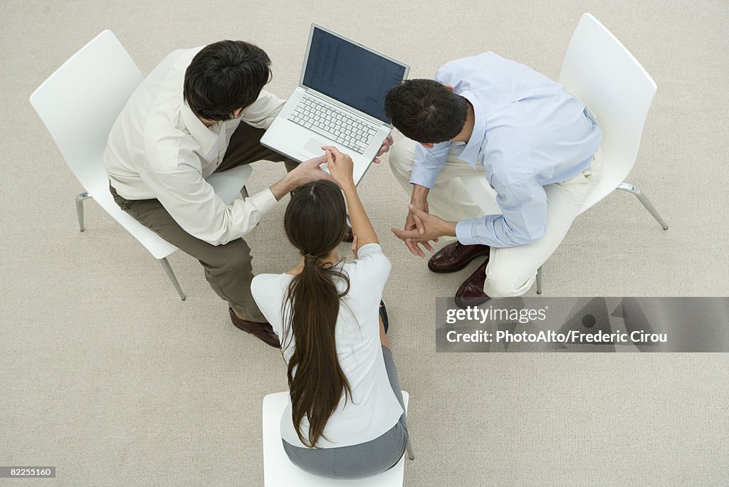 Colleagues looking at laptop computer together, overhead view