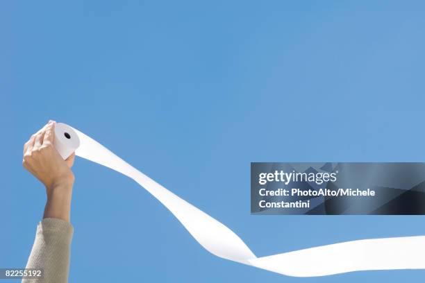 hand holding roll of paper in front of blue sky - carta igienica foto e immagini stock
