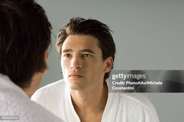 man examining his face in the mirror, wearing bathrobe - homem bonito imagens e fotografias de stock