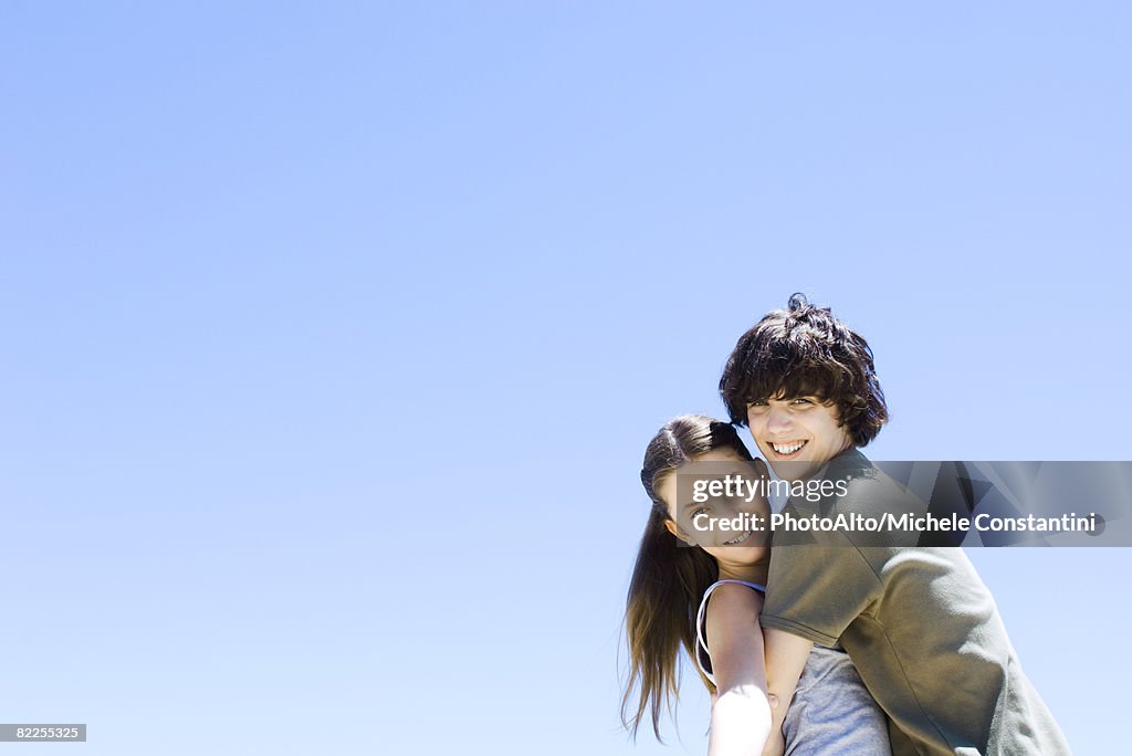 Brother hugging his sister, smiling at camera