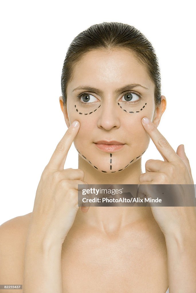 Woman with plastic surgery markings on face, touching cheeks, looking away