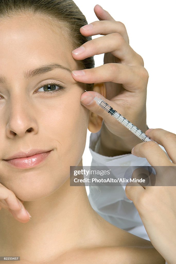 Young woman receiving Botox injection, cropped view