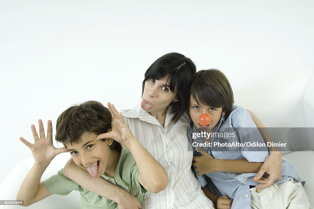 Mother and two sons, sticking out their tongues, one wearing clown's nose