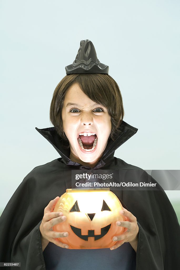 Boy holding jack o' lantern, looking at camera, open mouth, portrait