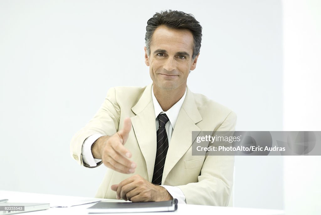 Businessman offering his hand to camera, smiling