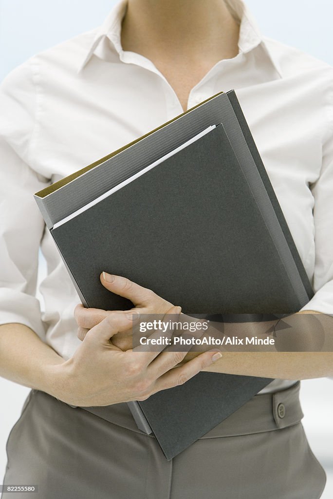 Female professional holding folders, cropped view