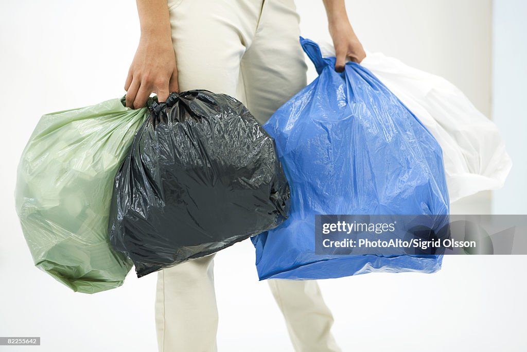 Female carrying several bags of garbage, cropped view