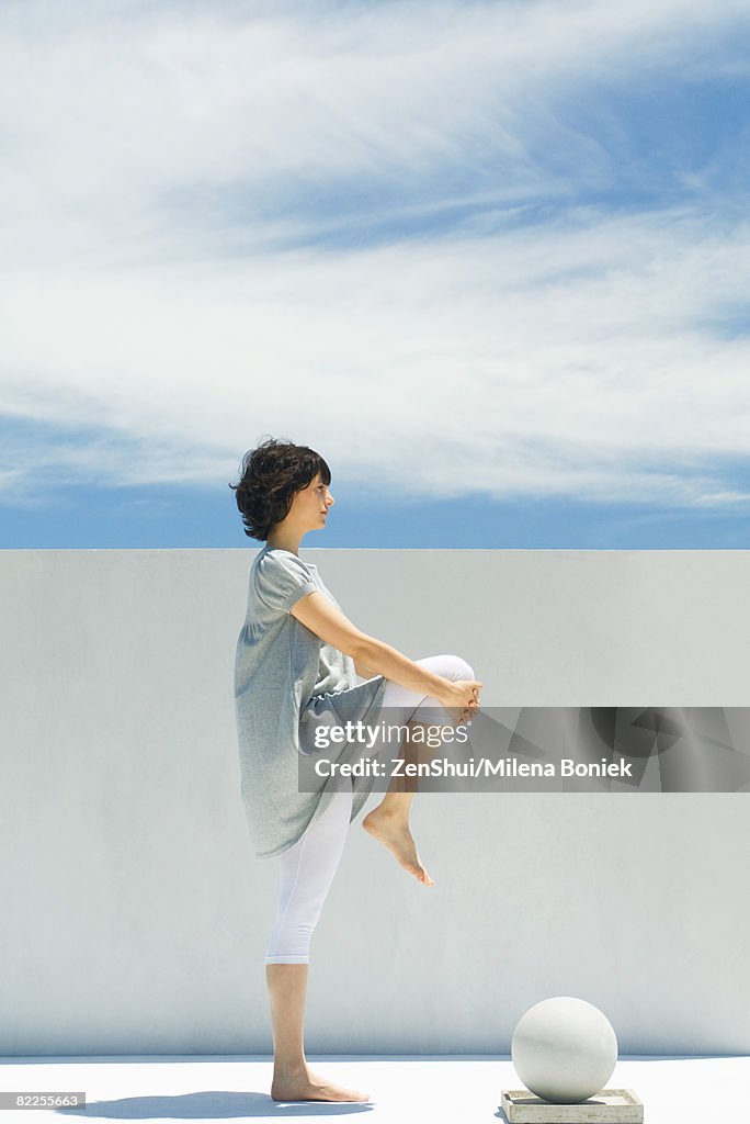 Woman stretching outdoors, side view