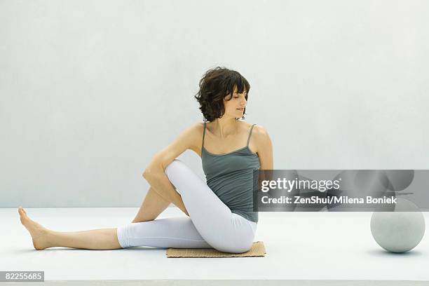 woman doing yoga on the ground, ball nearby - spinal twist stock pictures, royalty-free photos & images