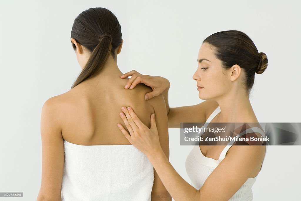 Massage therapist giving woman shoulder massage