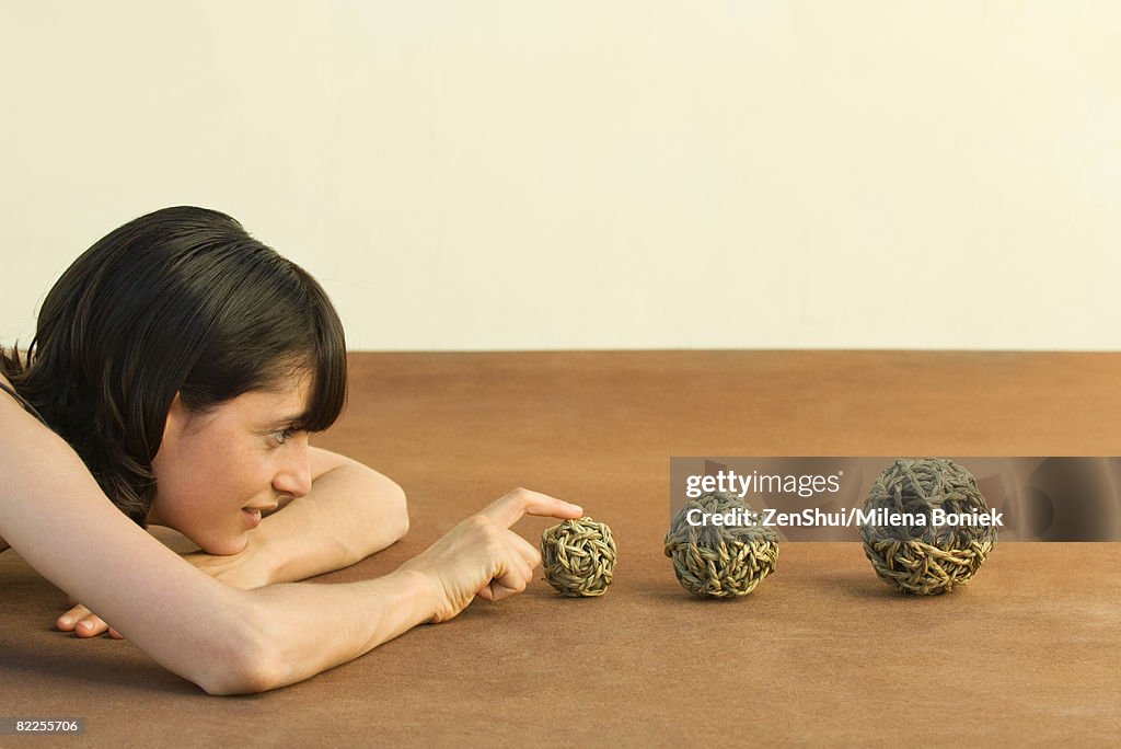 Woman resting head on arms, looking at balls of string, side view