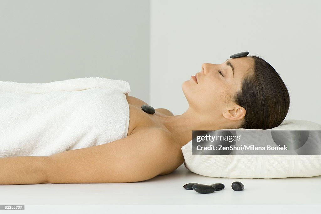 Woman undergoing lastone therapy, eyes closed