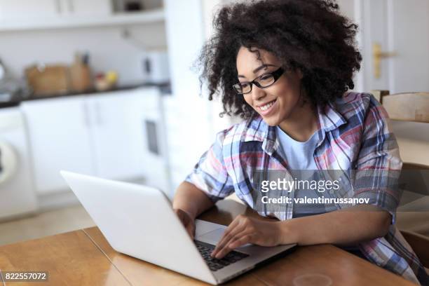 woman with eyeglasses using laptop at home - single female study stock pictures, royalty-free photos & images