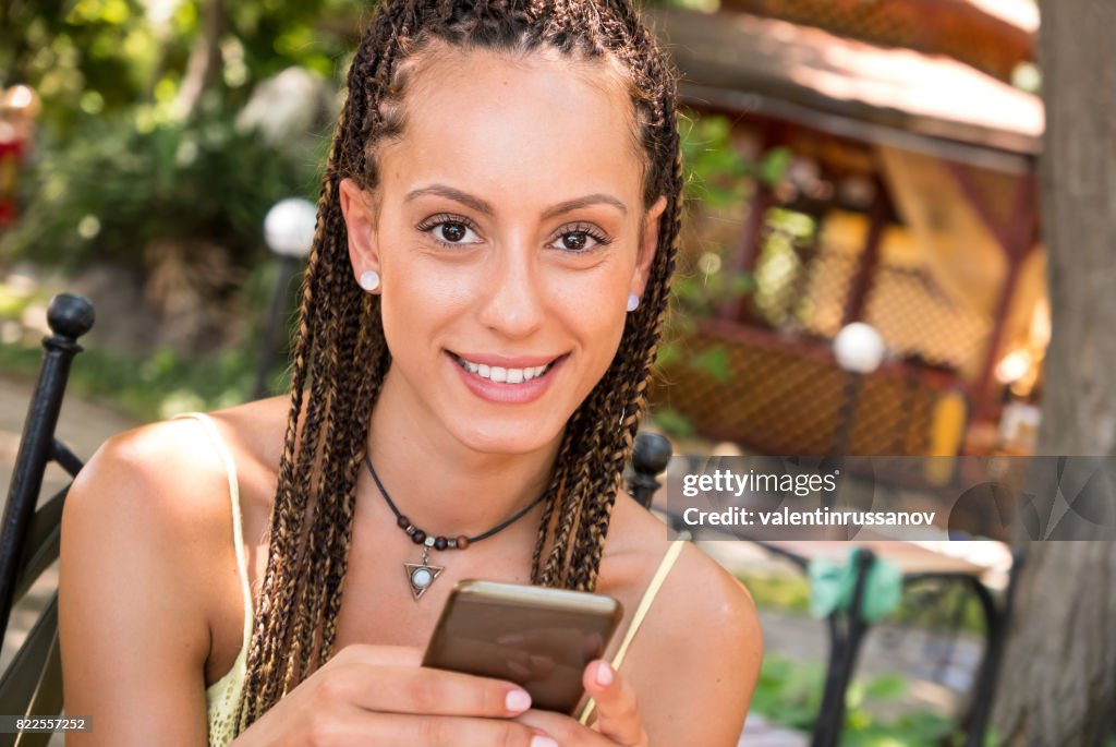 Smiling girl text messaging outdoors