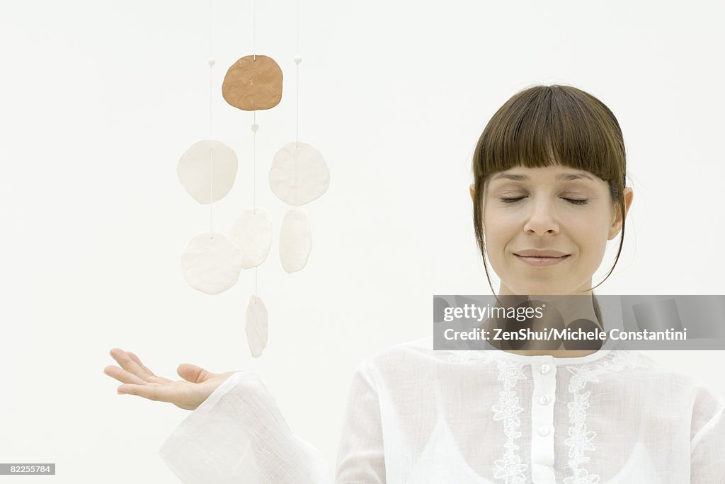 Woman meditating with decorative mobile