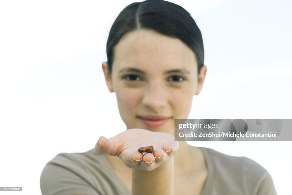 Young woman holding out dried bean in palm of hand