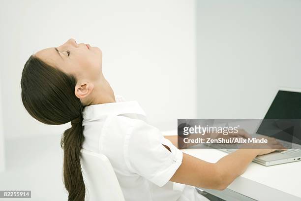 woman sitting in front of laptop, head back, eyes closed - cabeça para trás - fotografias e filmes do acervo