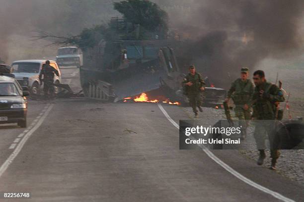 Georgian soldiers walk from the scene of a destroyed armoured vehicle on the road to Tbilisi on August 11, 2008 just outside Gori, Georgia. Russia...