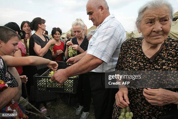 Refugees from South Ossetia share grapes in a camp visited by French Foreign Minister Bernard Kouchner on August 11 near the village of Alagir, is...