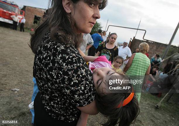 Refugee from South Ossetia carries a child as she stands in a camp visited by French Foreign Minister Bernard Kouchner on August 11 near the village...