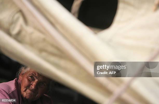 An elderly refugee from South Ossetia looks on as she sits under a tent in a camp visited by French Foreign Minister Bernard Kouchner on August 11...