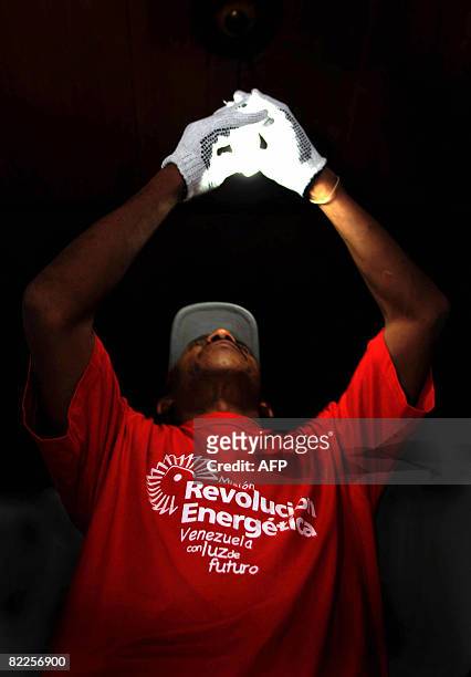 Member of the "Energy Revolution" project installs a low consumption light bulb in Caracas on August 8, 2008. The project, which is organized by the...