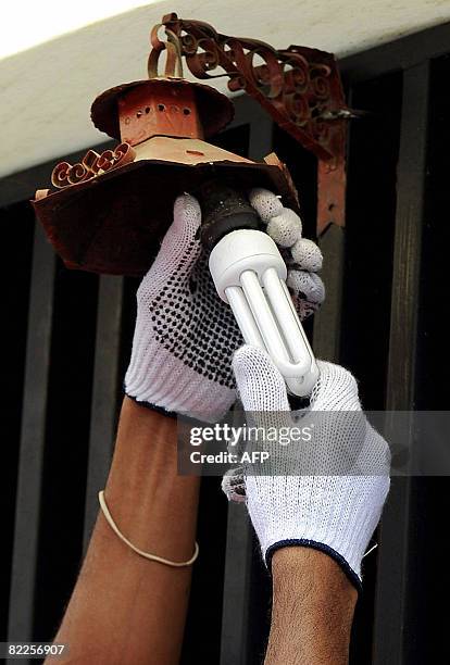 Member of the "Energy Revolution" project installs a low consumption light bulb in Caracas on August 8, 2008. The project, which is organized by the...