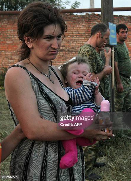 Woman from South Ossetia looks on as she carries a baby in a refugee camp visited by French Foreign Minister Bernard Kouchner on August 11 near the...