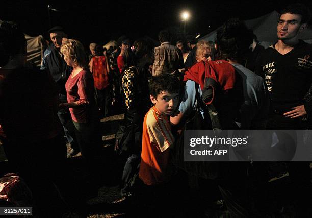 Refugees from South Ossetia stand at night in a refugee camp visited by French Foreign Minister Bernard Kouchner on August 11 near the village of...