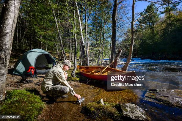 man camping at the riverbank with a canoe - ontario canada stock-fotos und bilder
