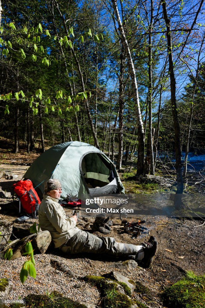 Man camping at the riverbank with a canoe