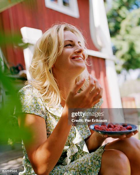 a smiling woman eating strawberries sweden. - woman eating fruit imagens e fotografias de stock