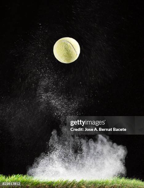 impact and rebound of a ball of tennis on a surface of grass and powder on a black background - ballon rebond stock pictures, royalty-free photos & images