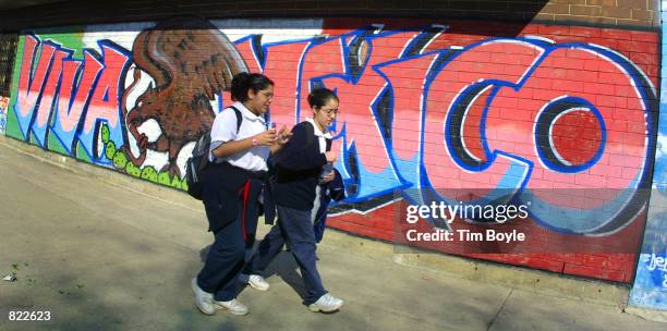 Two Hispanic girls walk past a "Viva Mexico" wall mural after school March 21, 2001 in Chicago's mainly Hispanic Pilsen neighborhood. The city's...