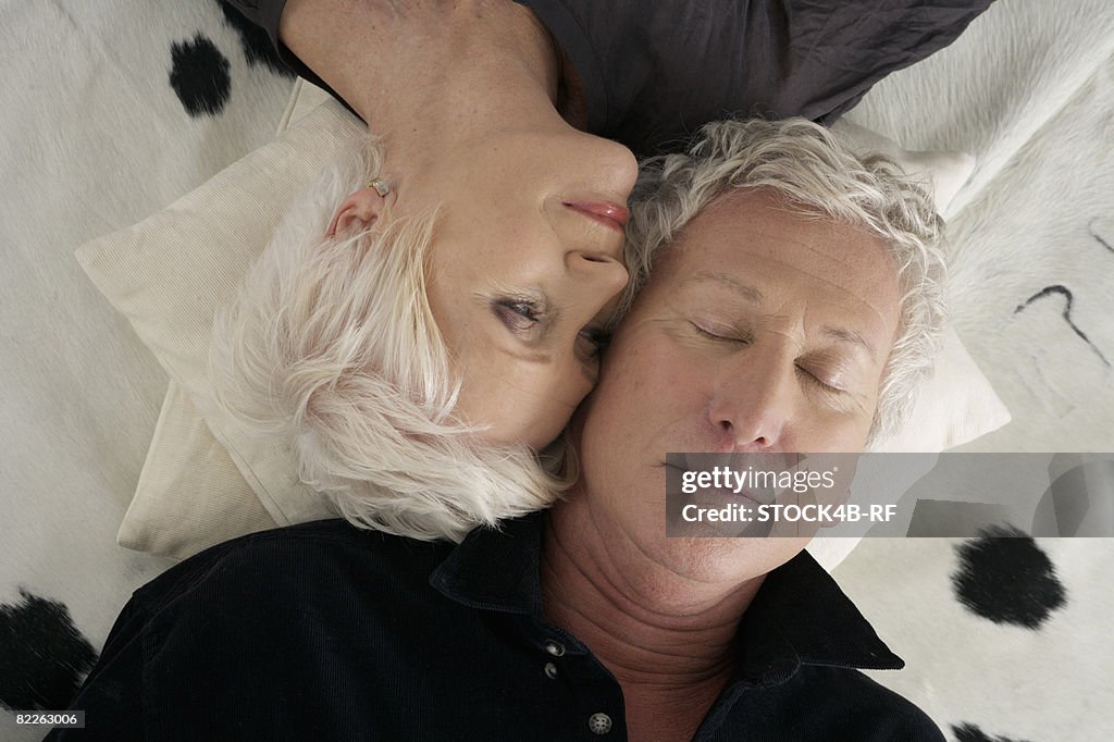 Senior couple lying head to head on a cowskin