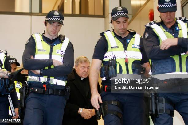 Cardinal Pell walks with a heavy Police guard from his barristers Robert Richter office to the Melbourne Magistrates' Court on July 26, 2017 in...
