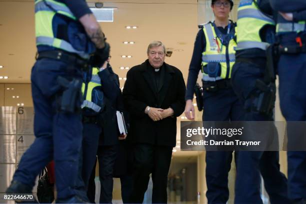 Cardinal Pell walks with a heavy Police guard from his barristers Robert Richter office to the Melbourne Magistrates' Court on July 26, 2017 in...