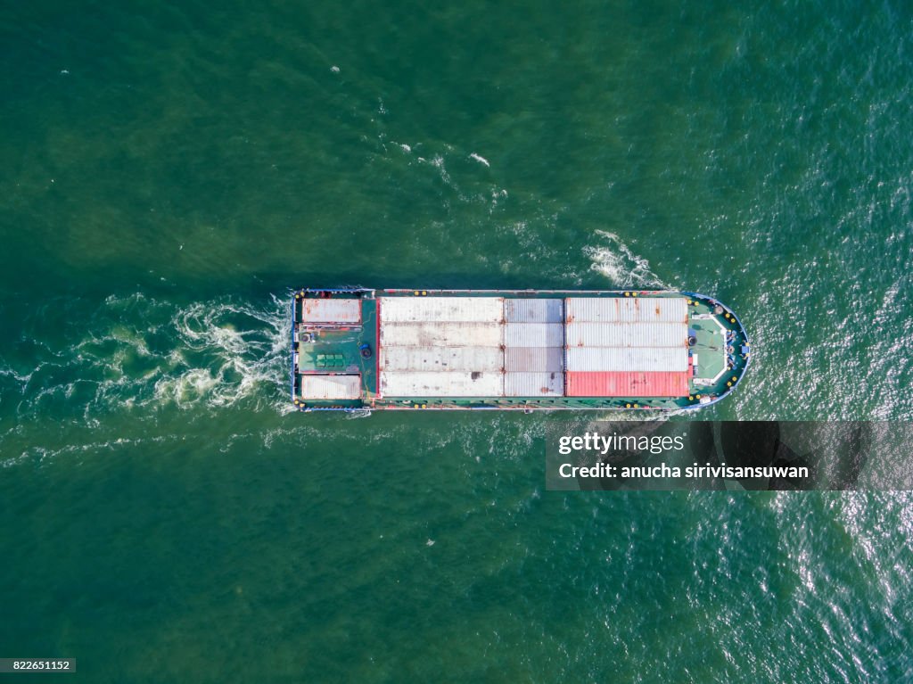 Aeriel view container shipping by Small transport container ship by green sea .