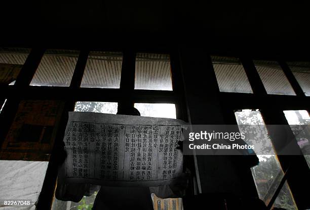 Taoist priest checks a scroll printed with the traditional method of woodblock typography at Qingyang Gong, a Taoist temple built during the Eastern...