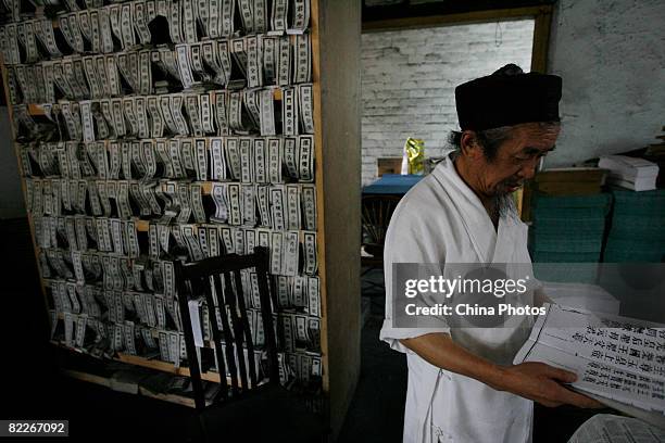 Taoist priest checks books printed with the traditional method of woodblock typography at Qingyang Gong, a Taoist temple built during the Eastern Han...
