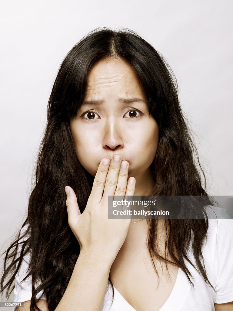 Young asian woman with hand over her mouth