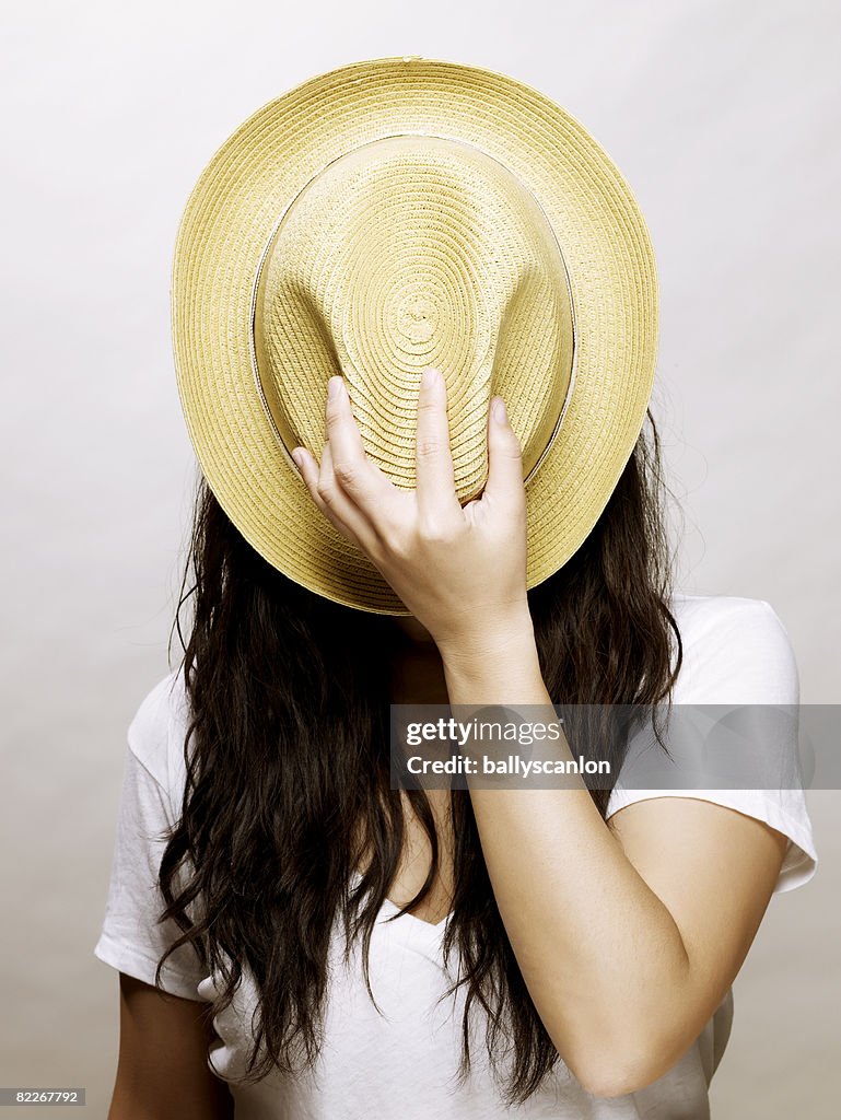 Young asian woman covering face with a straw hat