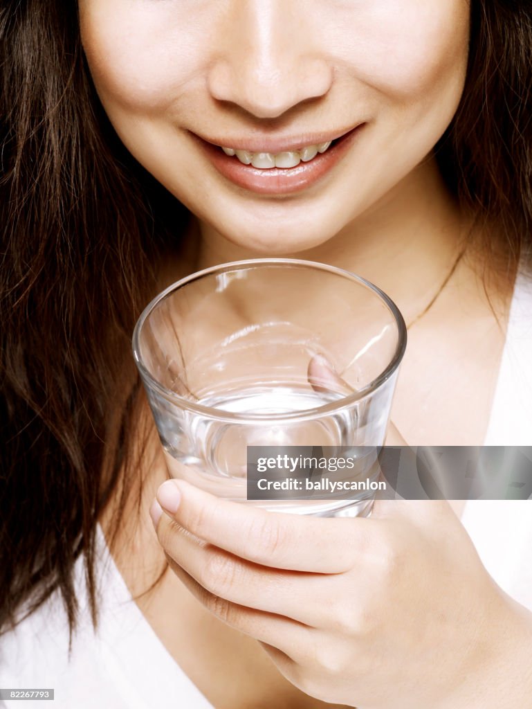 Young asian woman holding a glass of water